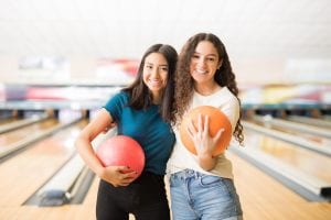 Female Friends With Bowling Balls Hanging Out In Alley